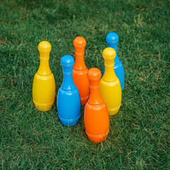 Children's set to play bowling on green grass. Ball and colored pins. Kid's game toy. Bowling colorful plastic pins. Active and interesting childhood concept.
