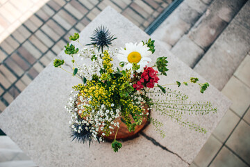 Bouquet with daisy and thistle on a stone pedestal. Wedding flower.