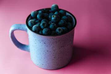 fresh blueberries in a blue cup on a pink background. with the place for copy space.