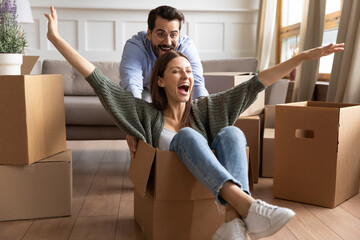Happy family celebrating moving day, playful young couple having fun at home, funny activity,...