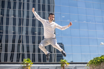 Joven exitoso en el entorno laboral muy feliz saltando para celebrar un ascenso en el trabajo