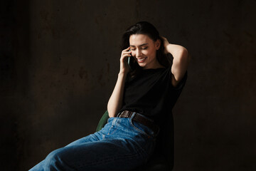 Photo of beautiful woman sitting on chair and talking on cellphone