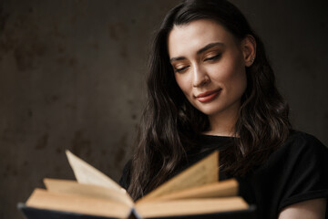 Photo of beautiful young brunette woman smiling and reading book