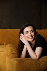 Obraz premium Photo of young woman smiling and lying on couch in modern apartment