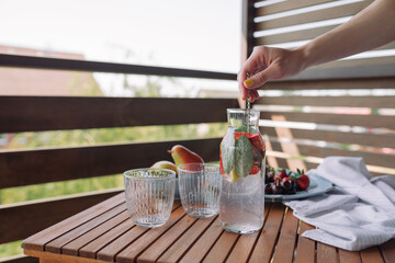 Woman making healthy lemonade on the summer terrace.