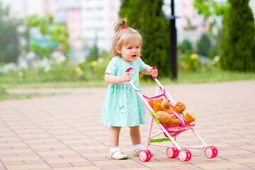 beautiful  cute baby child plays with baby stroller caring positive association care .walk rest in the park with mom
