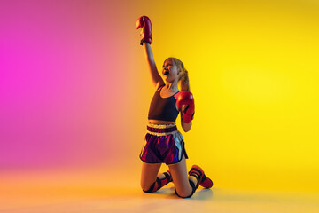 Fototapeta na wymiar Little caucasian girl, kick boxer on gradient background in neon light, active and expressive. Concept of motion, action, motivation, childhood. Successful winner, emotional. Sales, ad, copyspace.