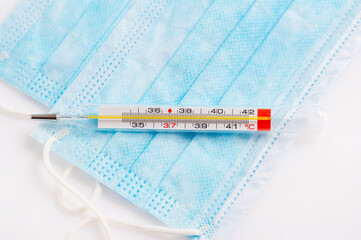 Close up of mercury thermometer with medical mask mask
