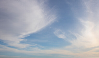 Naklejka na ściany i meble Whispy clouds on a sunny blue sky background.