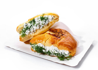 Fragrant muffin stuffed with cottage cheese and dill on a paper plate on a white background.