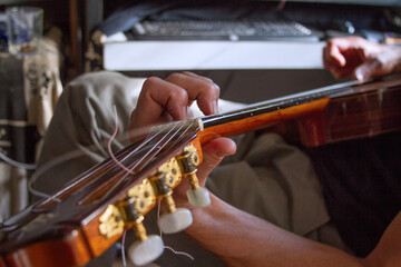 Close up of man's hand playing flamenco guitar with computer in the background.