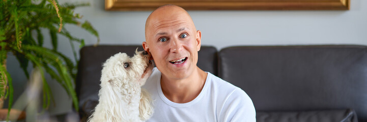 Handsome man with cute white dog at home
