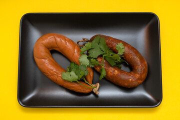 smoked sausages on black dish on yellow paper background