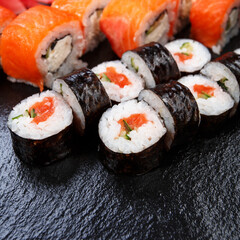 Various kinds of sushi served on stone background.
