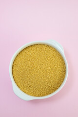 couscous in white bowl on pink paper background