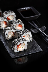 Japanese sushi with soy sauce and chopsticks on black background.