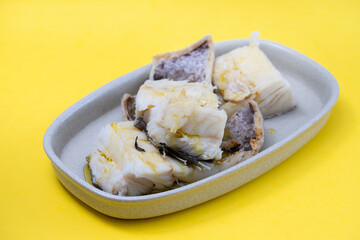 boiled cod fish on dish on yellow paper background