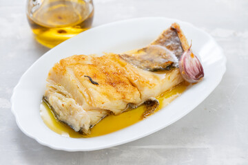 fried cod fish with garlic and olive oil on white dish