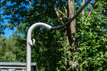 An electric wire in a black corrugation is connected to the house through a metal pipe bent down,...