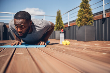 Concentrated international man doing push-ups on terrace