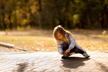 little girl in coat in autumn plays with toy car on remote control in Park. 