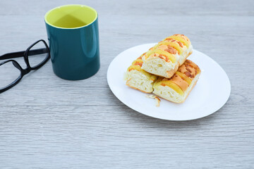 Loaves of cheese bread, a mug of coffee and eyeglasses on wooden table 
