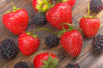 blackberries, strawberrieson wooden table background, spilled from a spice jar. Antioxidants, detox diet, organic fruits. Top view. Berries
