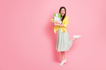 Full body photo of funny lady hold hands close to chest large green giftbox overjoyed amazing surprise wear yellow leather jacket long skirt shoes isolated pastel pink color background
