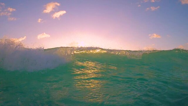 SLOW MOTION, UNDERWATER: Massive turquoise barrel wave breaks over the camera on a sunny summer evening in the scenic Caribbean. Cinematic view of a crystal clear breaking ocean wave at golden sunset.