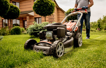 Gardener mowing the lawn. Landscape design. Green grass background