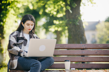 Young student watching lesson online and studying from park. Woman college university student using laptop computer. Studying working with pc technology online education concept.