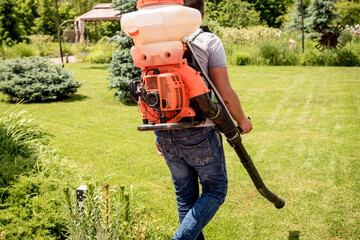 Gardener in protective mask and glasses spraying toxic pesticides trees