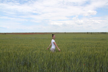 Young woman walking in the field toward the sun holding a poppy flower