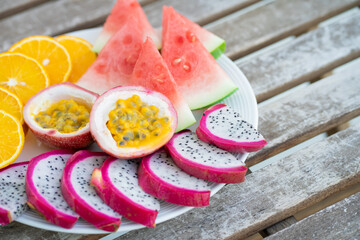White plate of sliced fruit. Fresh fruits and vitamins. Still life colored summer fruits.