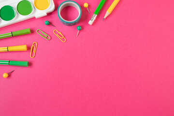Concept back to school. School stationery flat lay: pens, pencils, sharpener, ruler, paper clips on bright pink paper background. Copyspace.
