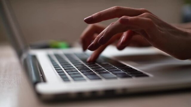 Close-up of hands of unrecognizable business woman typing on laptop keyboard, no face. Female freelancer or student is working writing post comments in social networks sitting at desk at home office.