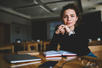 Portrait of attractive young woman student sitting with notebook and laptop computer for studying while looking at camera and sitting in university interior.Copy space area for advertising text