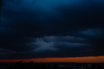 Black thunderclouds at sunset. Bright orange sunset and dark clouds. Storm sky