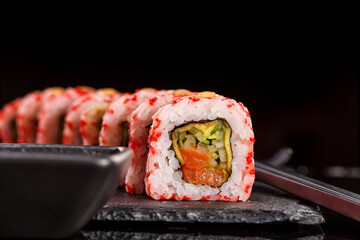 Japanese sushi with soy sauce and chopsticks on black background.