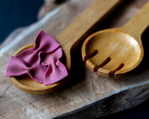 pink farfalle pasta bows on wooden spoon