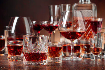 Set of strong alcoholic beverages in glasses on a brown background.