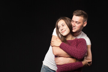 Smiling happy loving couple in studio on black background 