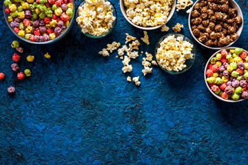 Colorful popcorn in paper box on blue background top view space for text