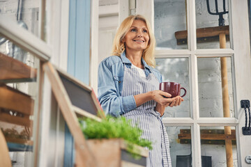 Cheerful woman holding a mug with both hands