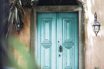 A turquoise blue old textured door, front view of a pink building