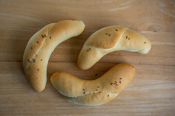 Three homemada handmade croissant rolls sprinkled with cumin, fresh very tasty crispy bakes on wooden table