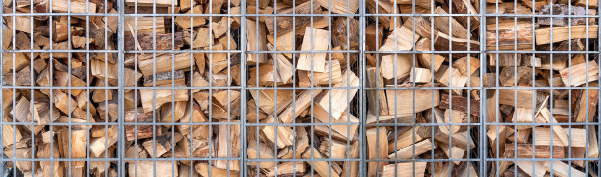 Brennholz in nebeneinanderstehenden Gitterboxen aus Metall - Panorama Detail