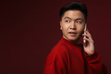 Image of serious handsome asian man talking on mobile phone