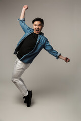 Image of delighted handsome asian man laughing and dancing