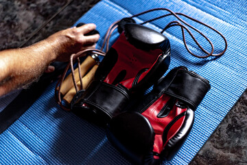 boxing gear ready to start training, black and red boxing gloves, leather skipping rope, black boxing slings and boxer picking it up for training